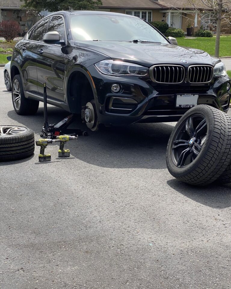 Photo of black car on a jack with tires in-front of the car.